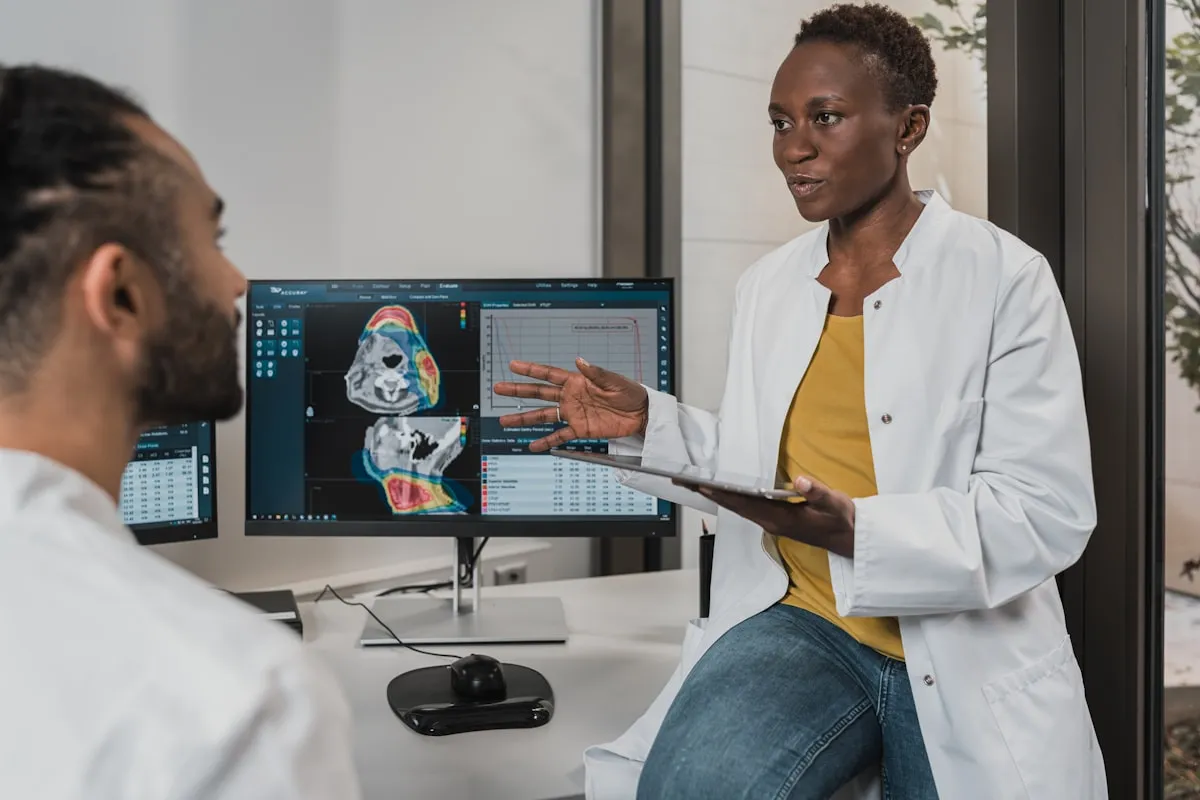 Two physicians discussing diagnostic scan results on a medical imaging workstation